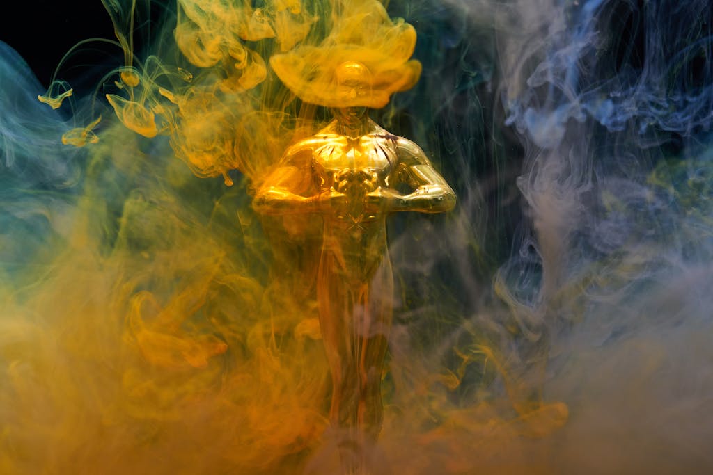 A golden statuette enveloped in vibrant yellow and blue smoke, symbolizing achievement and success.